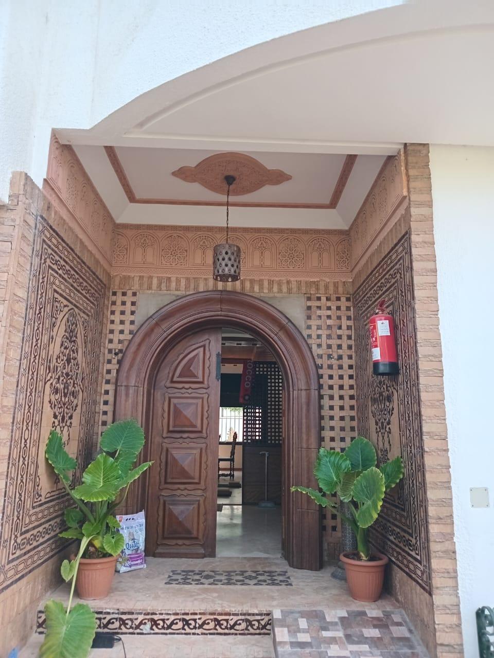 Entrée du centre Yoga You à Casablanca, porte en bois sculpté et zellige